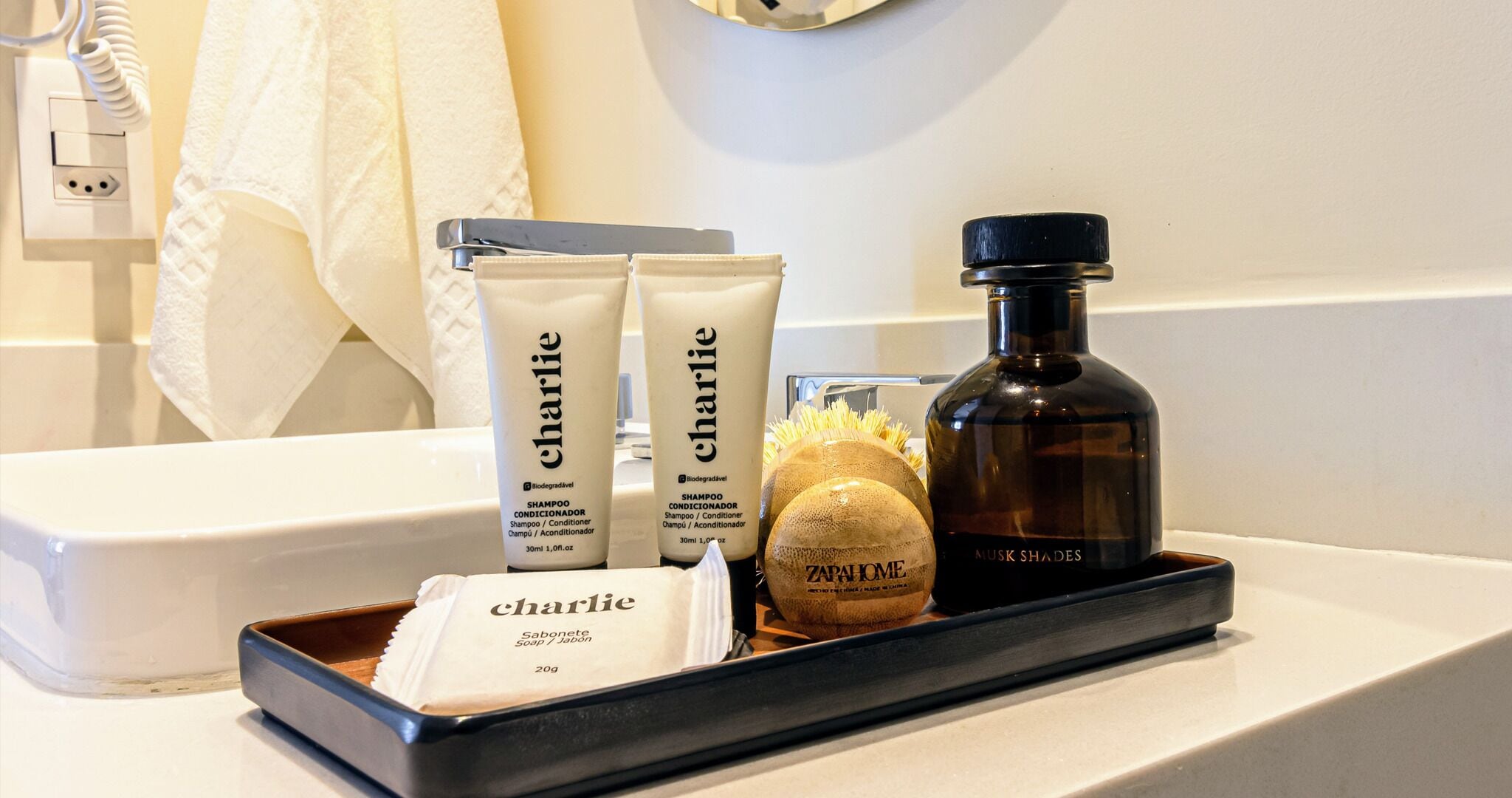 Toiletries on a bathroom counter, including a shampoo, conditioner, soap, and a bottle of shampoo.