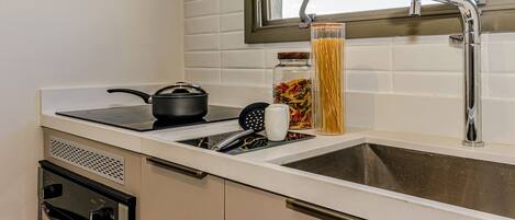 A modern kitchen with a stove, sink, and a window above the sink.