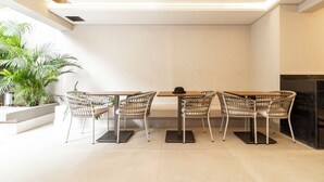 A modern dining area with a rectangular table and four wicker chairs, a potted plant, and a fireplace.