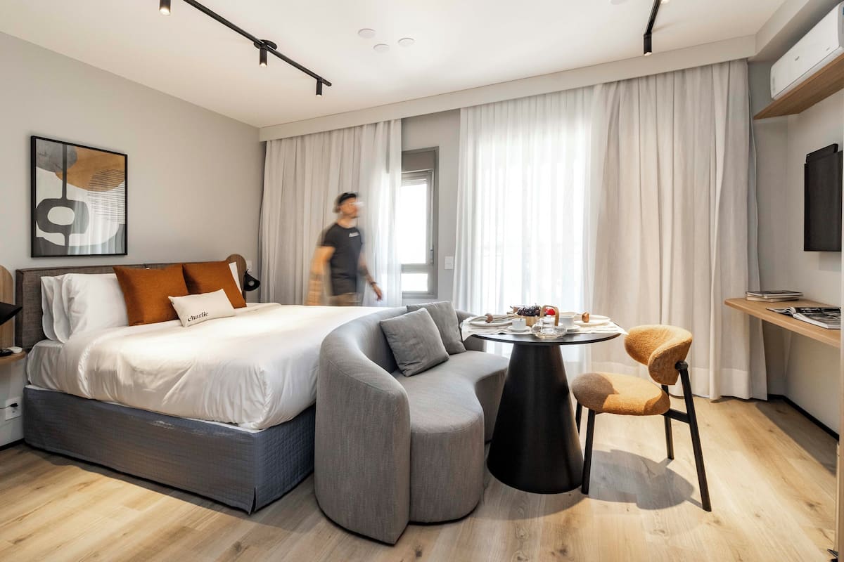 Une chambre d’hôtel moderne avec un canapé-lit incurvé, une petite table ronde et une chaise.