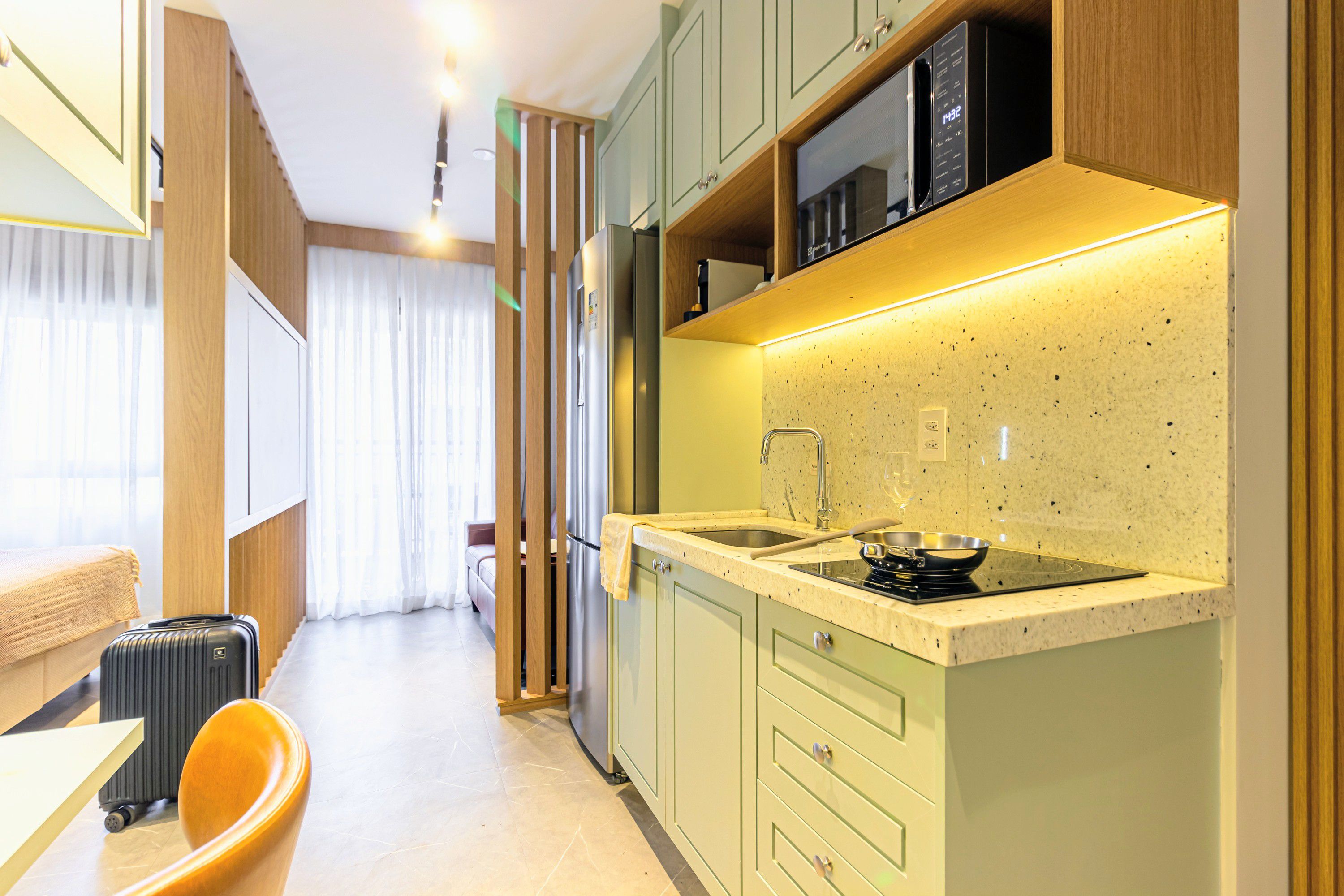 A compact kitchenette with a microwave, stove, and sink.