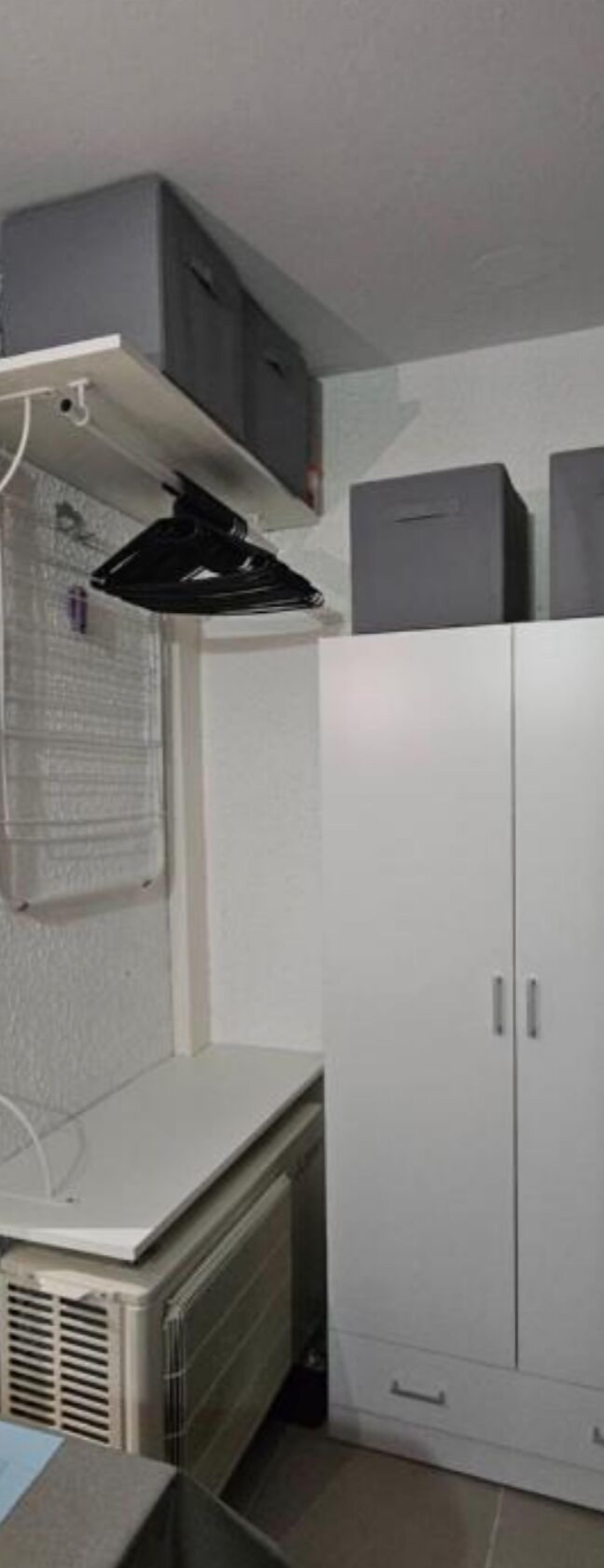 A room with a white wardrobe, a radiator, and a ceiling fan.