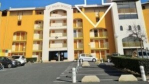 Un hotel de varios pisos con fachada amarilla y entrada blanca.
