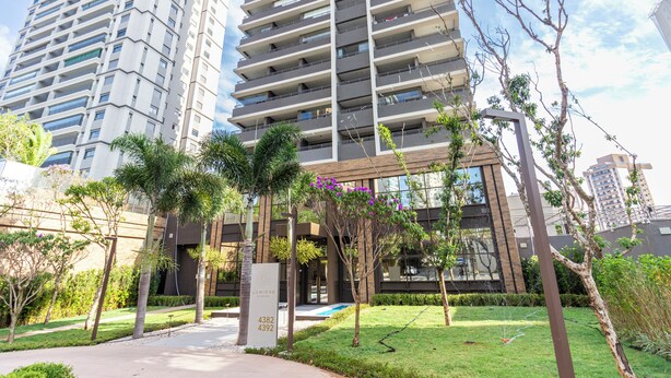 A modern high-rise building with multiple balconies, a well-maintained garden with palm trees, and a clear sky. - Charlie  Lumiere Klabin (São Paulo)