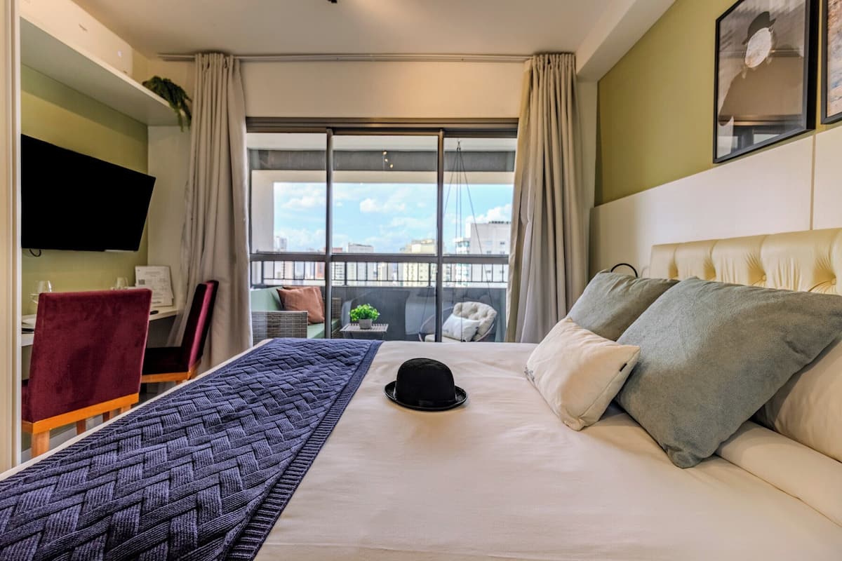 Una camera d'albergo con un letto, una televisione, una scrivania e una finestra vista città.