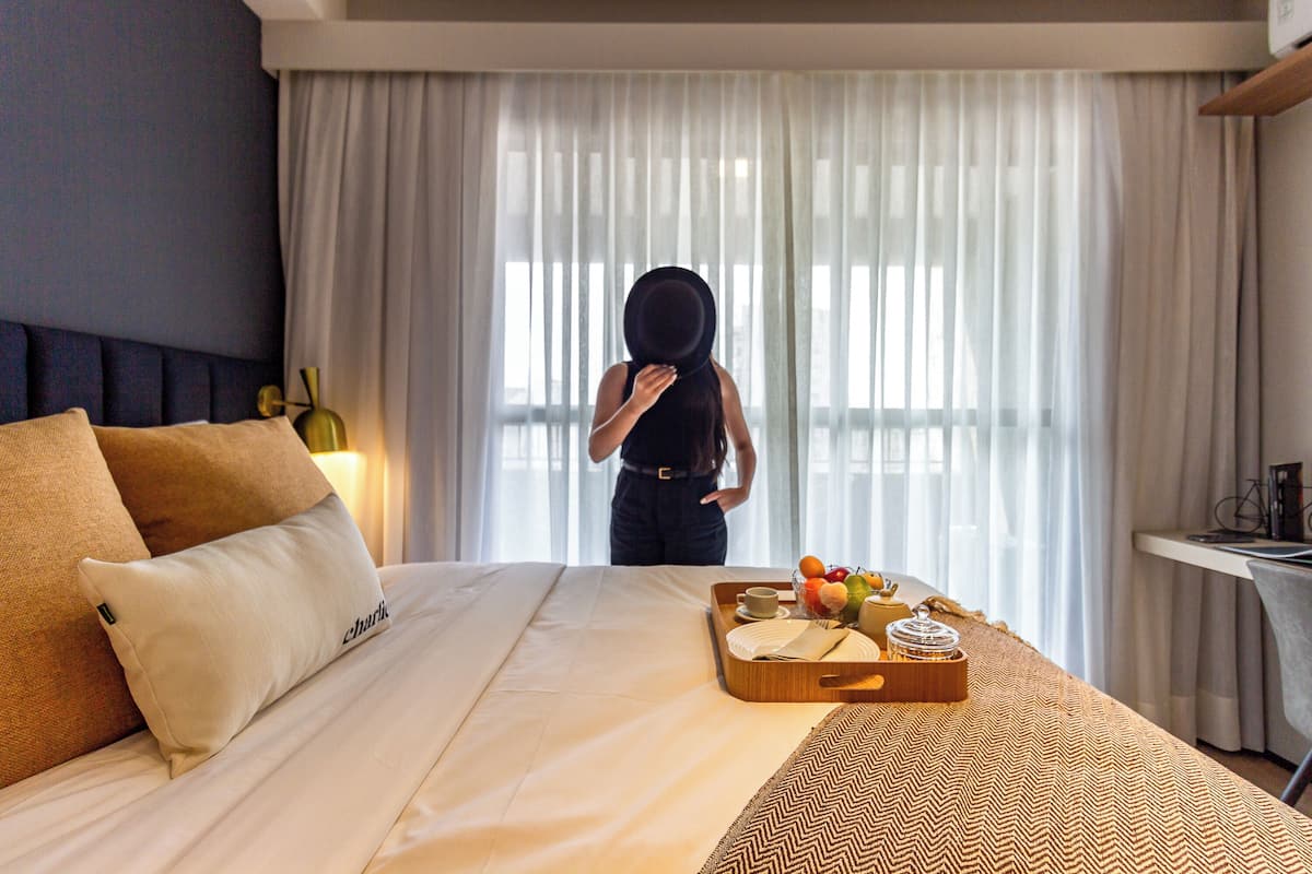 Una camera d'albergo con un letto, un vassoio con prodotti per la colazione e una finestra con tende.
