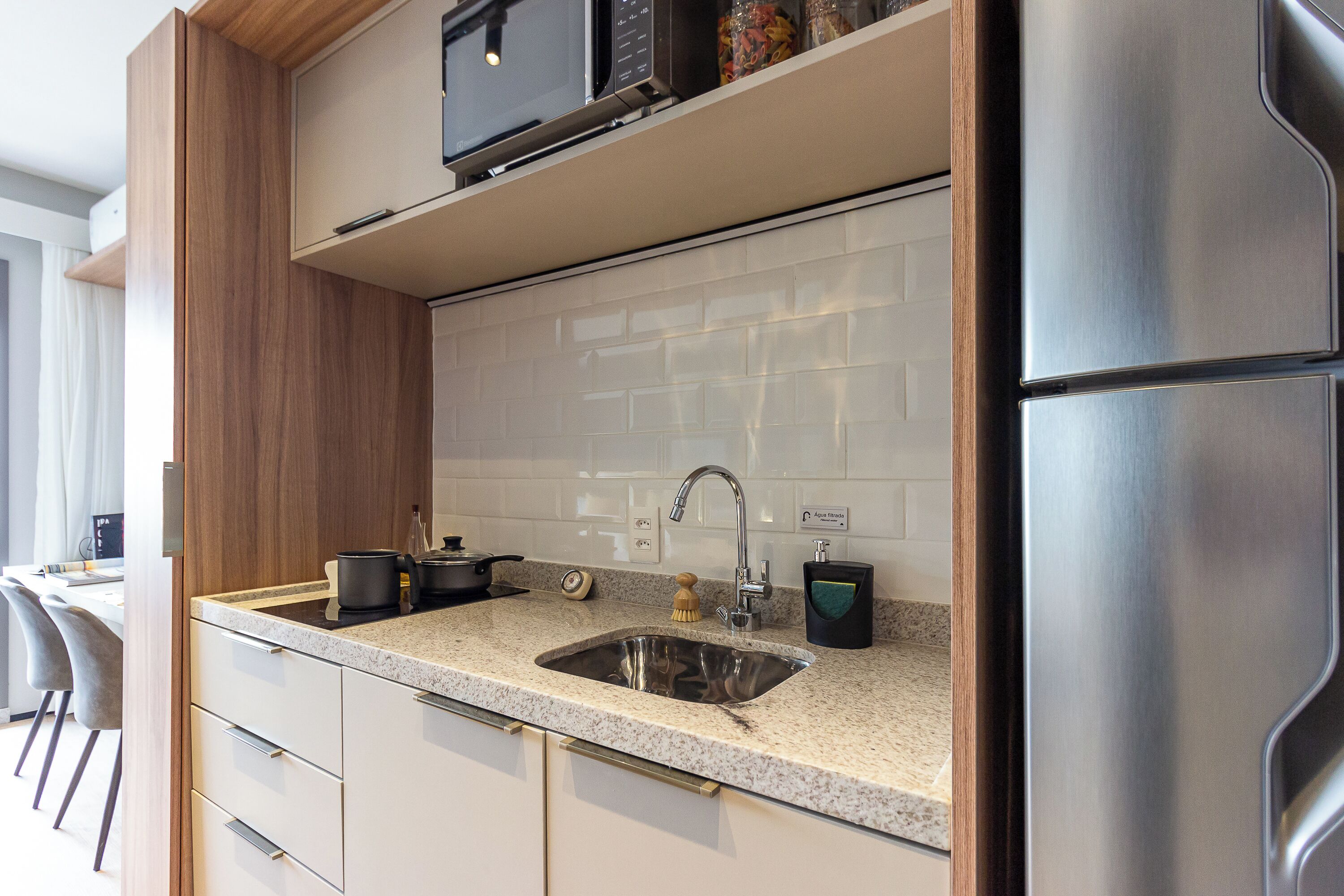 A modern kitchen with a stainless steel refrigerator, a double sink, and a microwave above the counter.