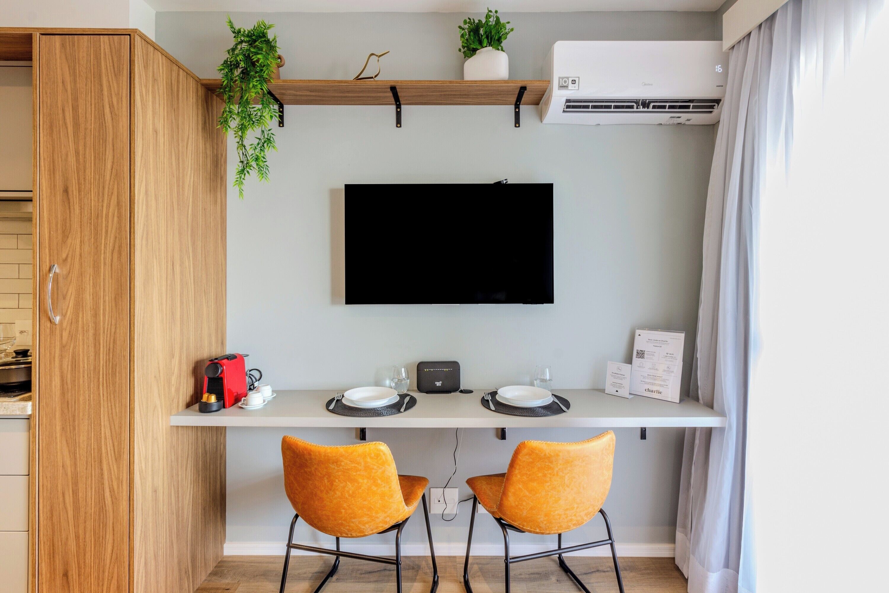 Una cocina moderna con horno empotrado, cafetera y televisor de pantalla plana montado en la pared.