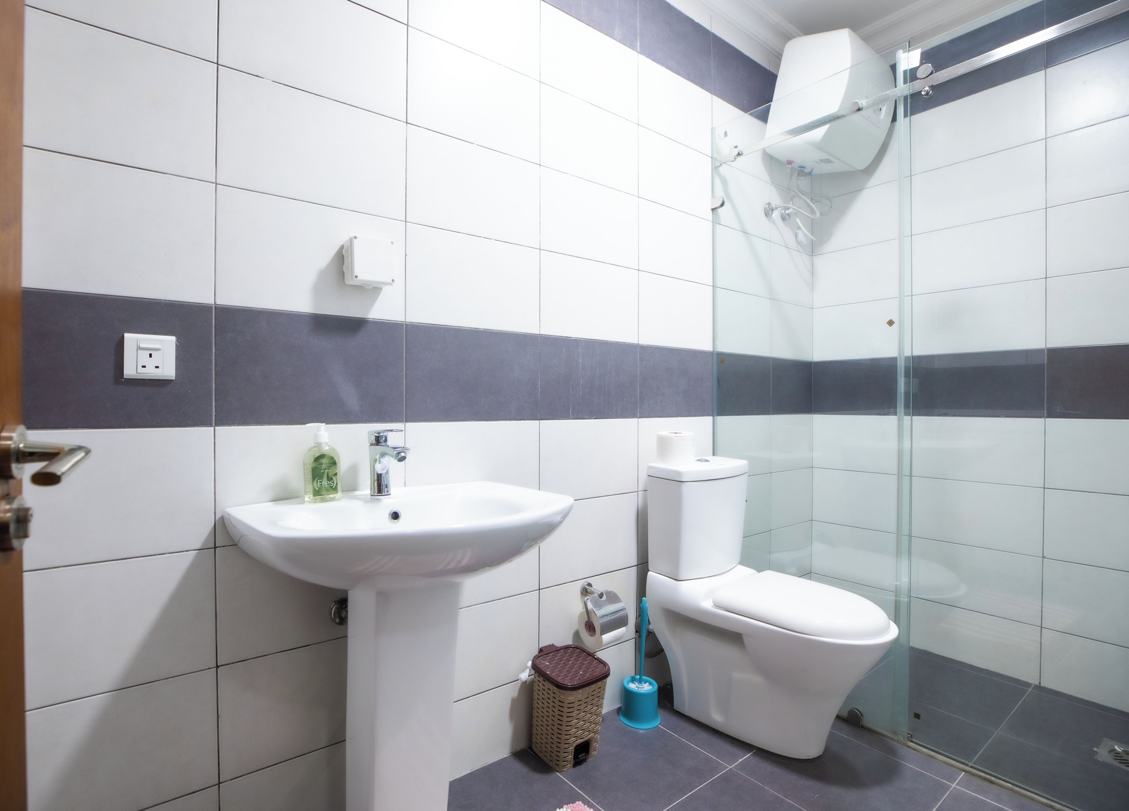 Et badeværelse med håndvask, toilet og brusekabine i glas.