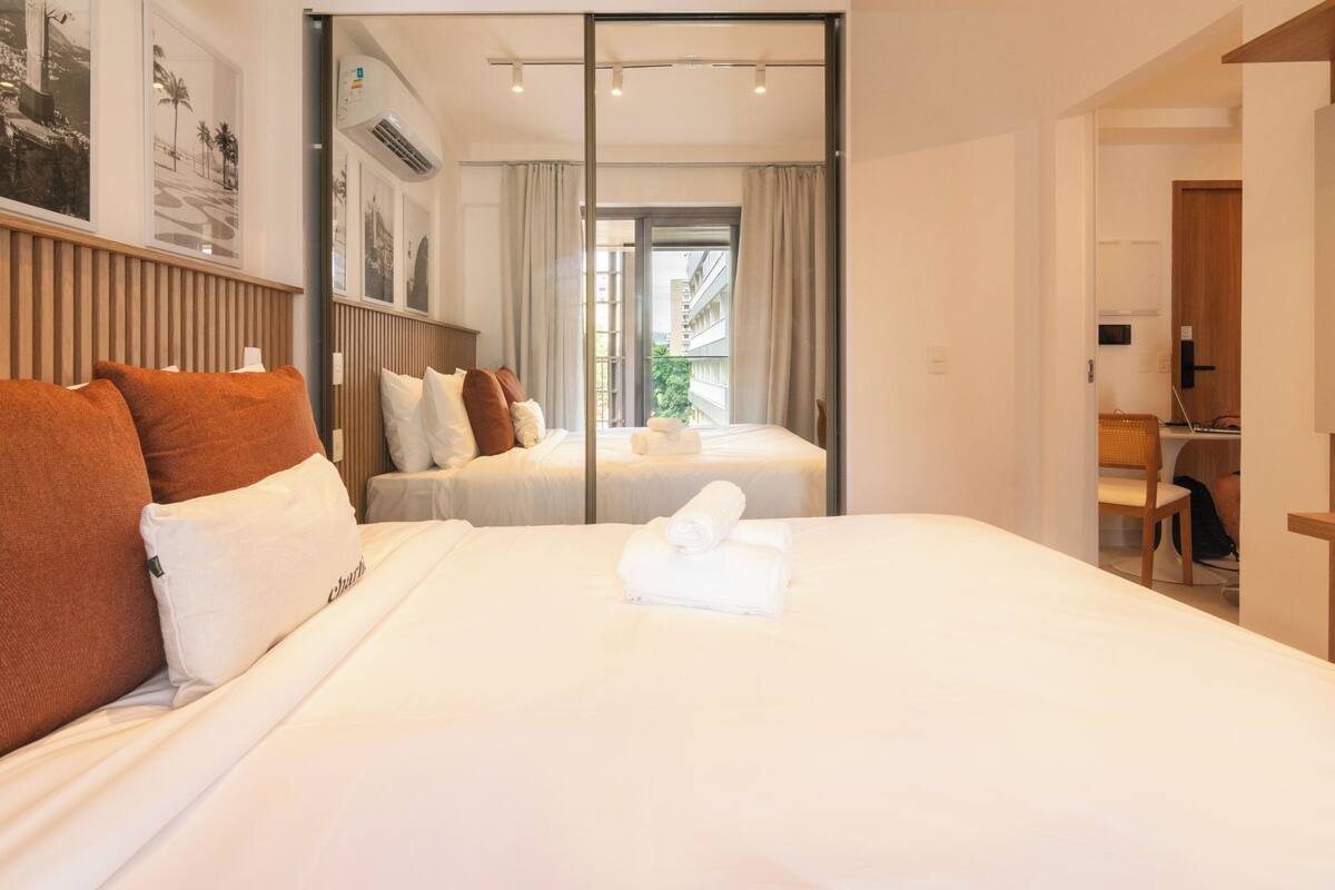 A hotel room with two beds, a large window, and a view of the outside.