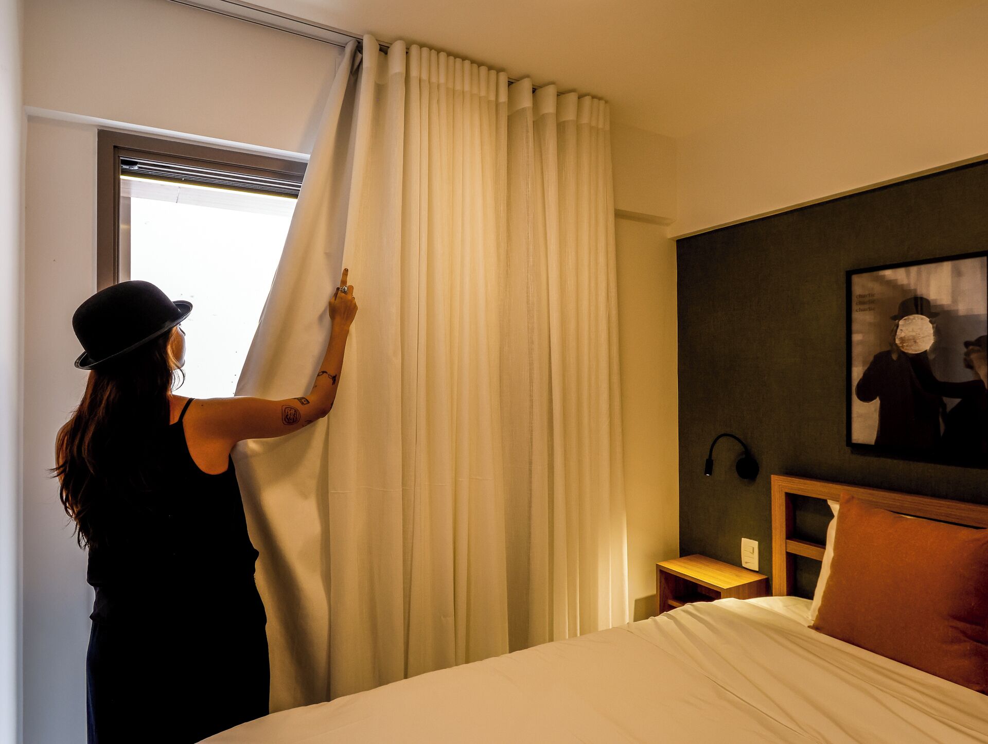 Una habitación de hotel con una cama, una mesita de noche, una lámpara y un cuadro en la pared.