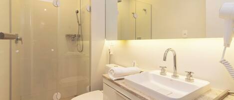 Une salle de bain moderne avec une douche à parois de verre, un lavabo blanc et un sèche-cheveux.