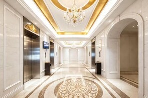 A hotel corridor with a chandelier, elevators, and a patterned floor. - Vienna International Hotel (Zhuzhou Railway Station Central Square Branch) (Zhuzhou)