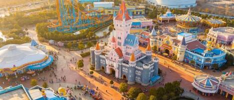 A theme park with various attractions, including a castle, roller coaster, and colorful buildings.