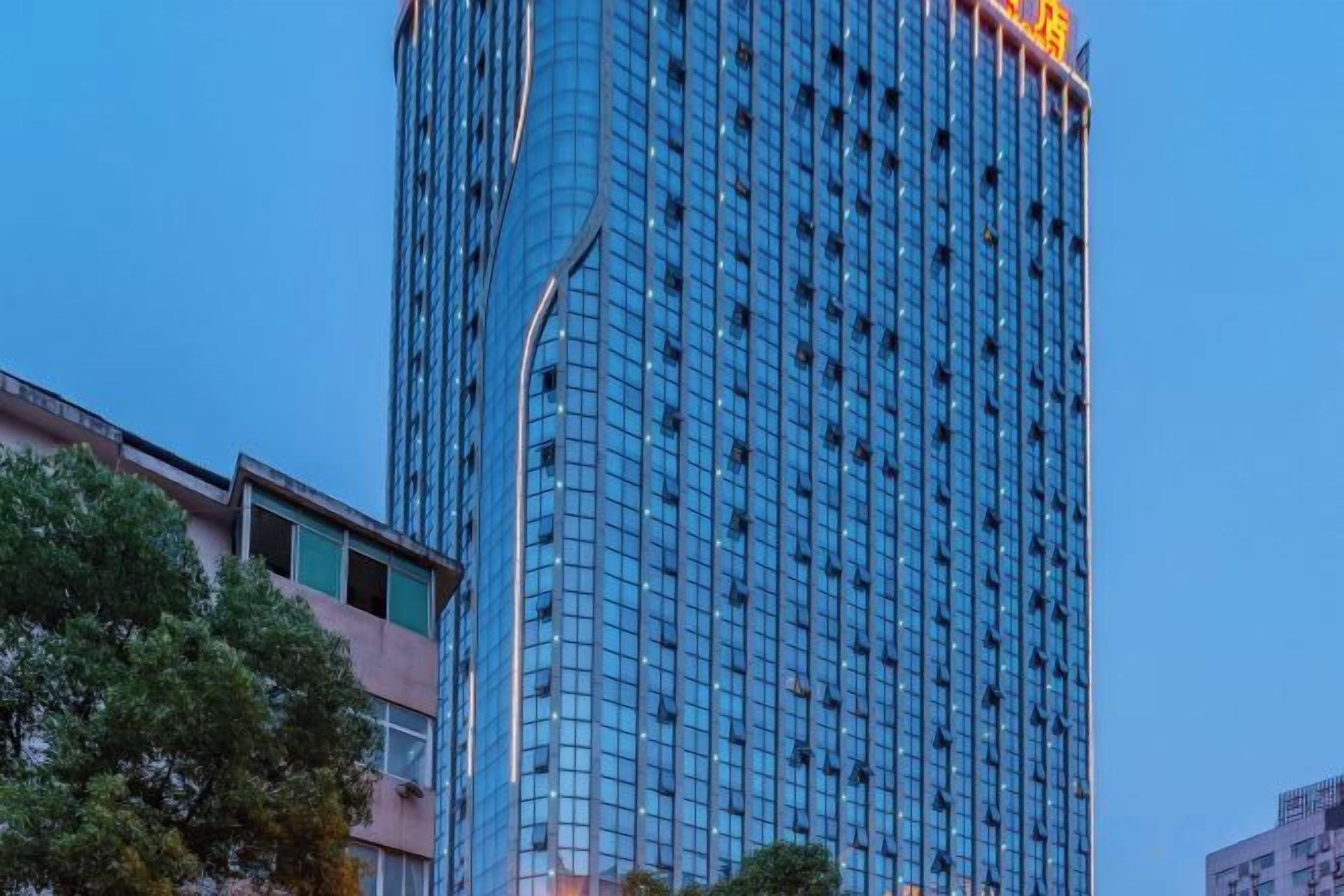 A tall, modern building with a glass facade and a prominent yellow sign at the top.