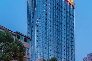 Un edificio alto y moderno con fachada de vidrio y un llamativo letrero amarillo en la parte superior.