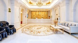 A spacious lobby with a reception desk, a chandelier, a white sofa, and a patterned floor. - Vienna International Hotel (Zhuzhou Railway Station Central Square Branch) (Zhuzhou)