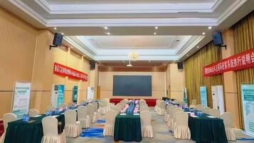 A conference room with a long table, chairs, and a projector screen.