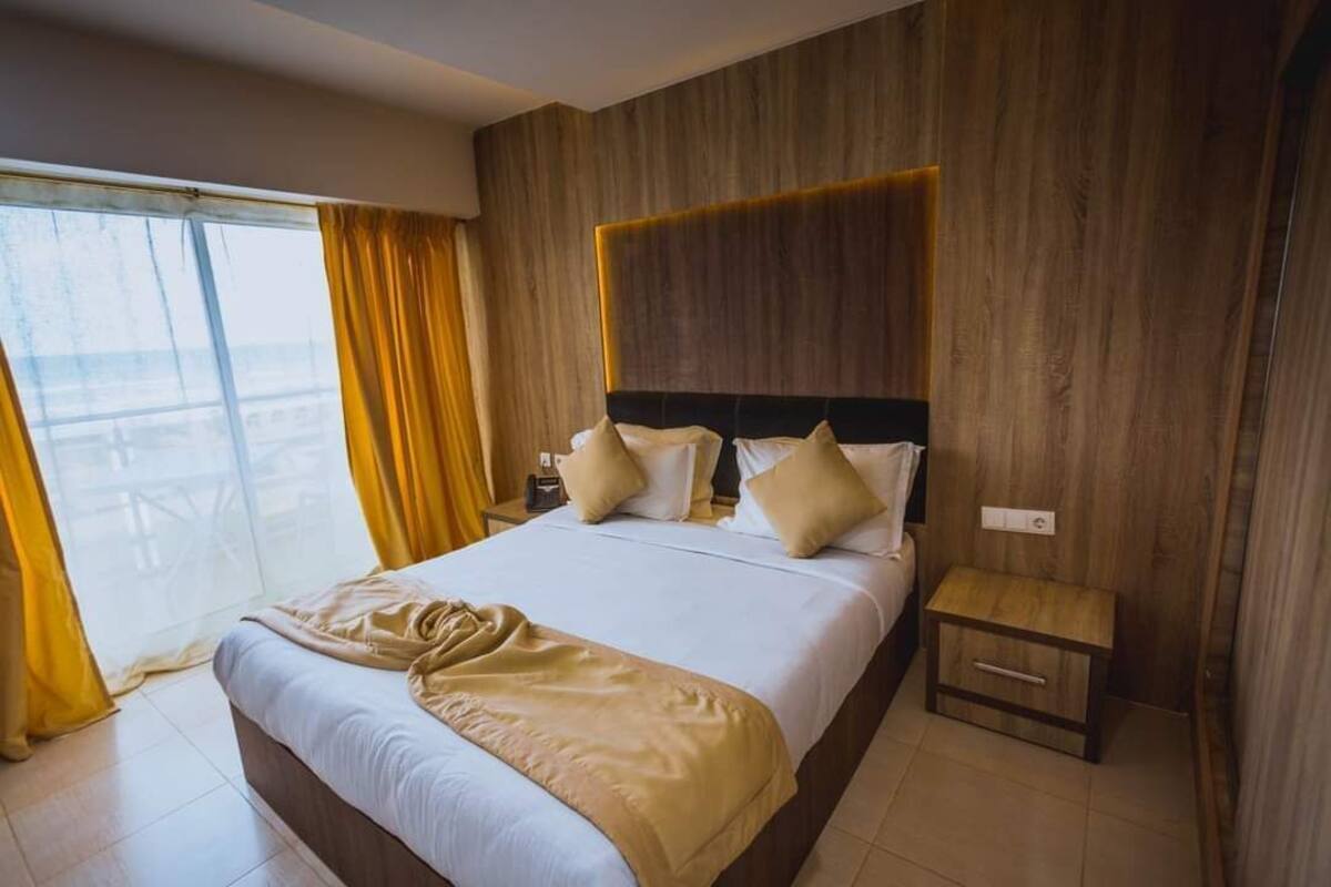 A hotel room with a large bed, wooden headboard, and a small bedside table.