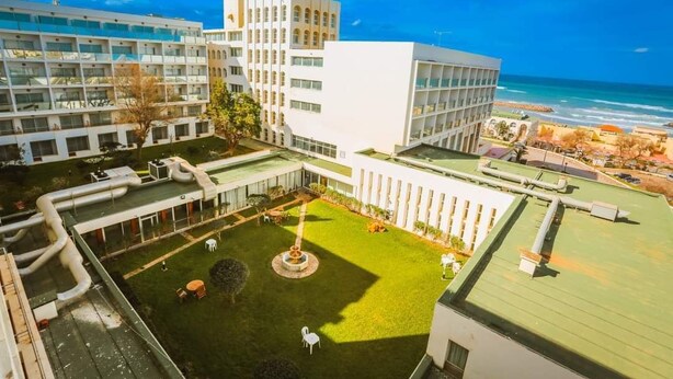 A modern hotel with multiple floors, a central courtyard with a fountain, and a view of the ocean. - Mazafran Zeralda (Algiers)