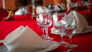 A dining table with white napkins and clear wine glasses, set against a red tablecloth. - Mazafran Zeralda (Algiers)