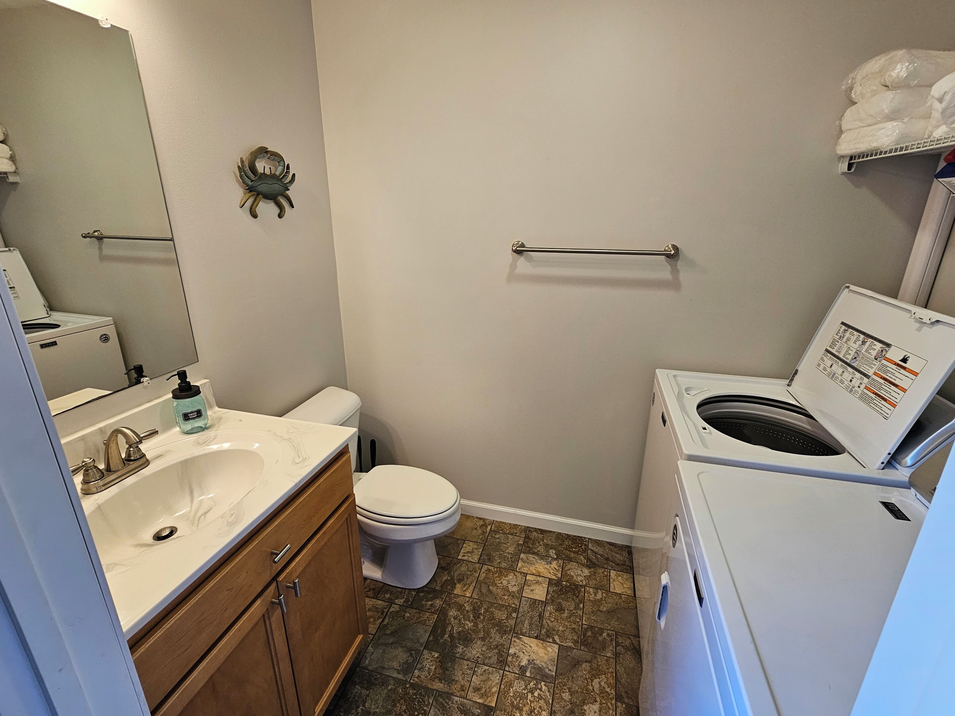 A compact bathroom with a sink, toilet, and washing machine.