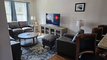 A living room with a sofa set, a coffee table, a TV, and a rug.