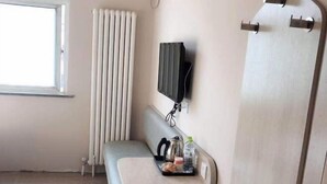 A room with a window, a radiator, a wall-mounted TV, a bench, and a tray with items. - Grace Inn (Jinan 960 Hospital, Zoo) (Jinan)