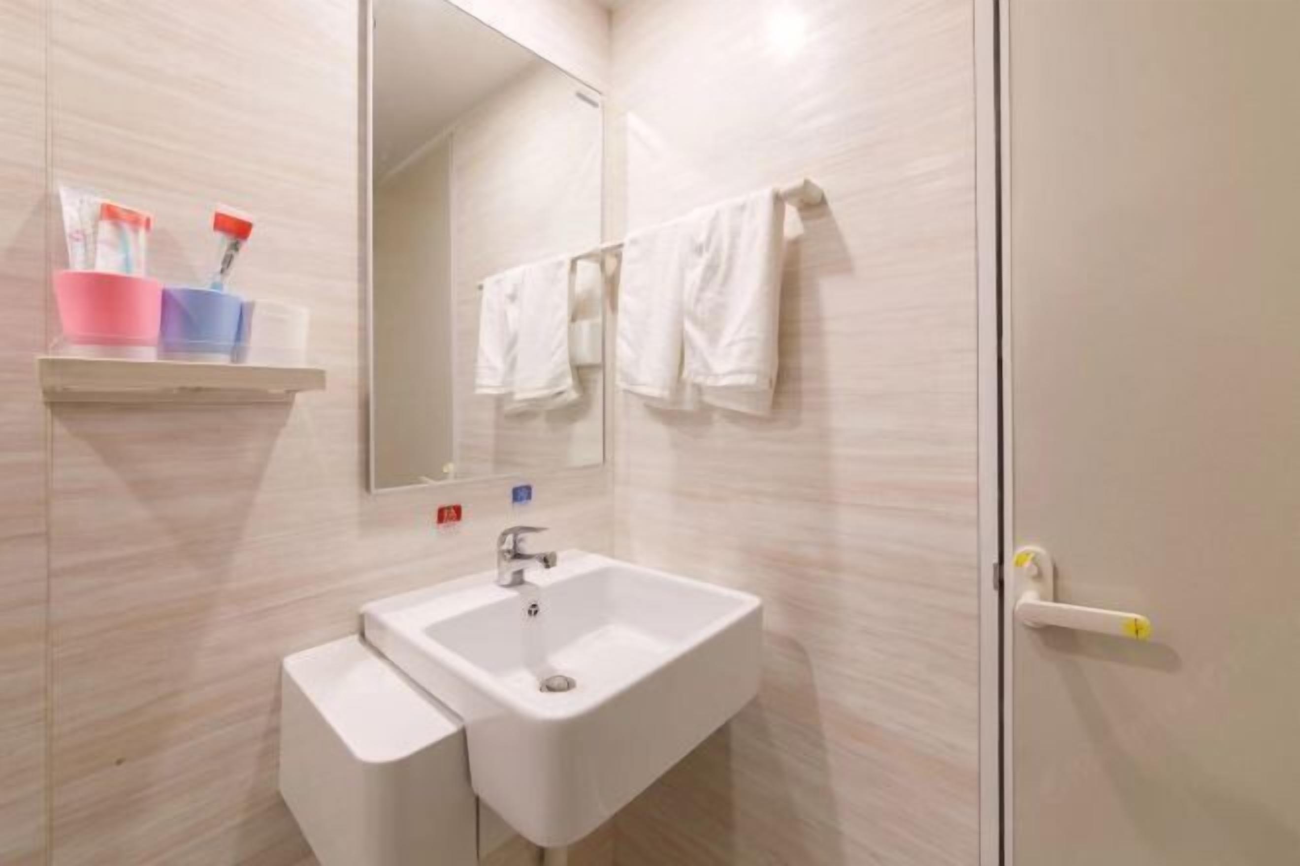 A bathroom with a white sink, a mirror, and a towel rack.