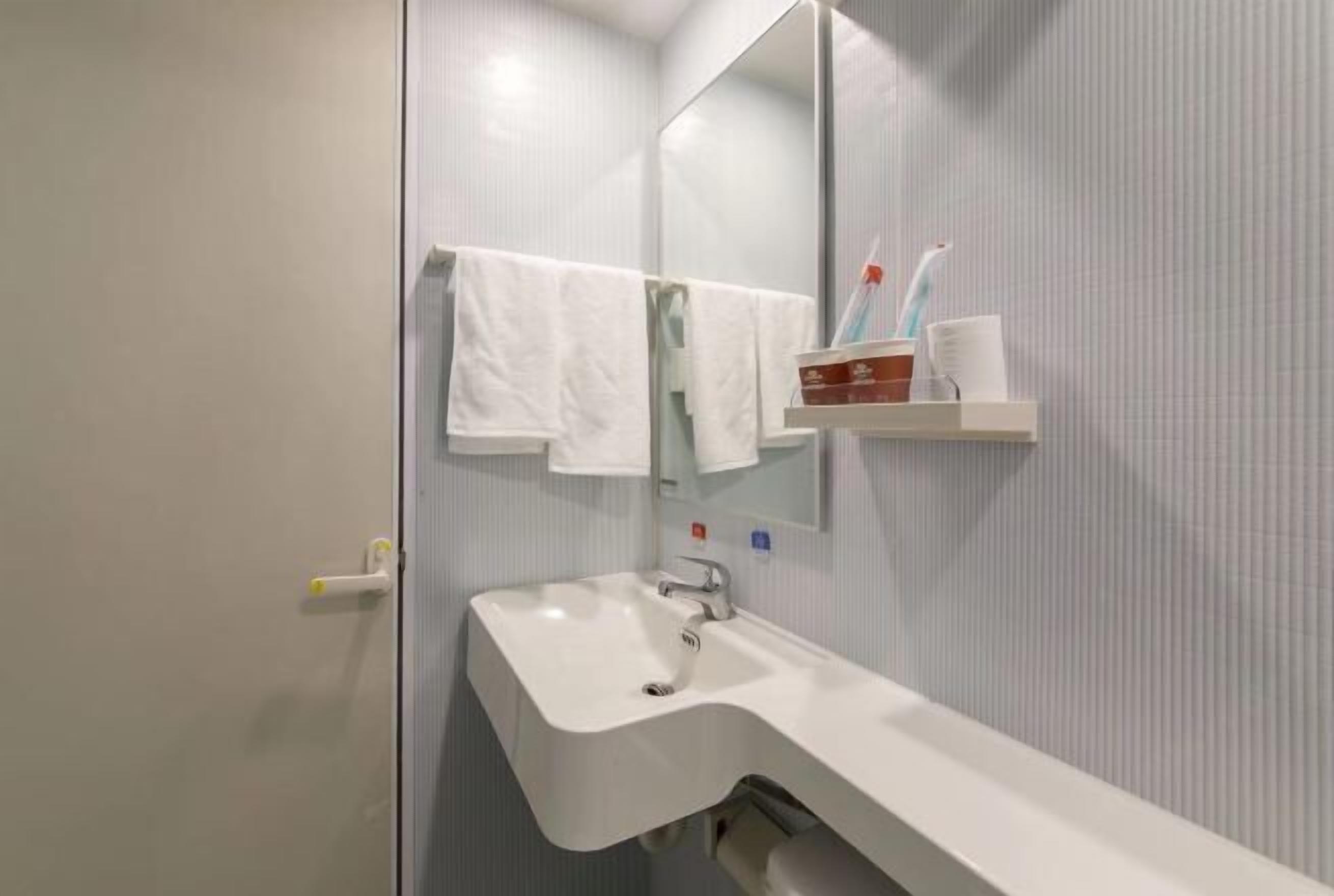 A bathroom with a white sink, a mirror, and a towel rack.