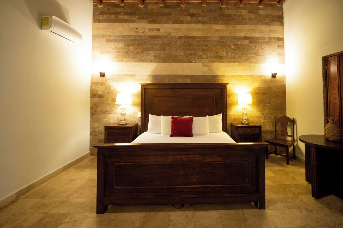 Une chambre à coucher avec un lit en bois, deux tables de chevet, une commode, une chaise et une lampe.