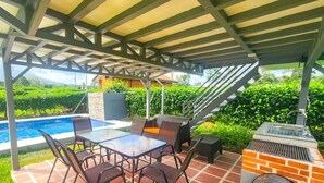 En udendørs terrasse med pool, grill og overdækket siddeområde.