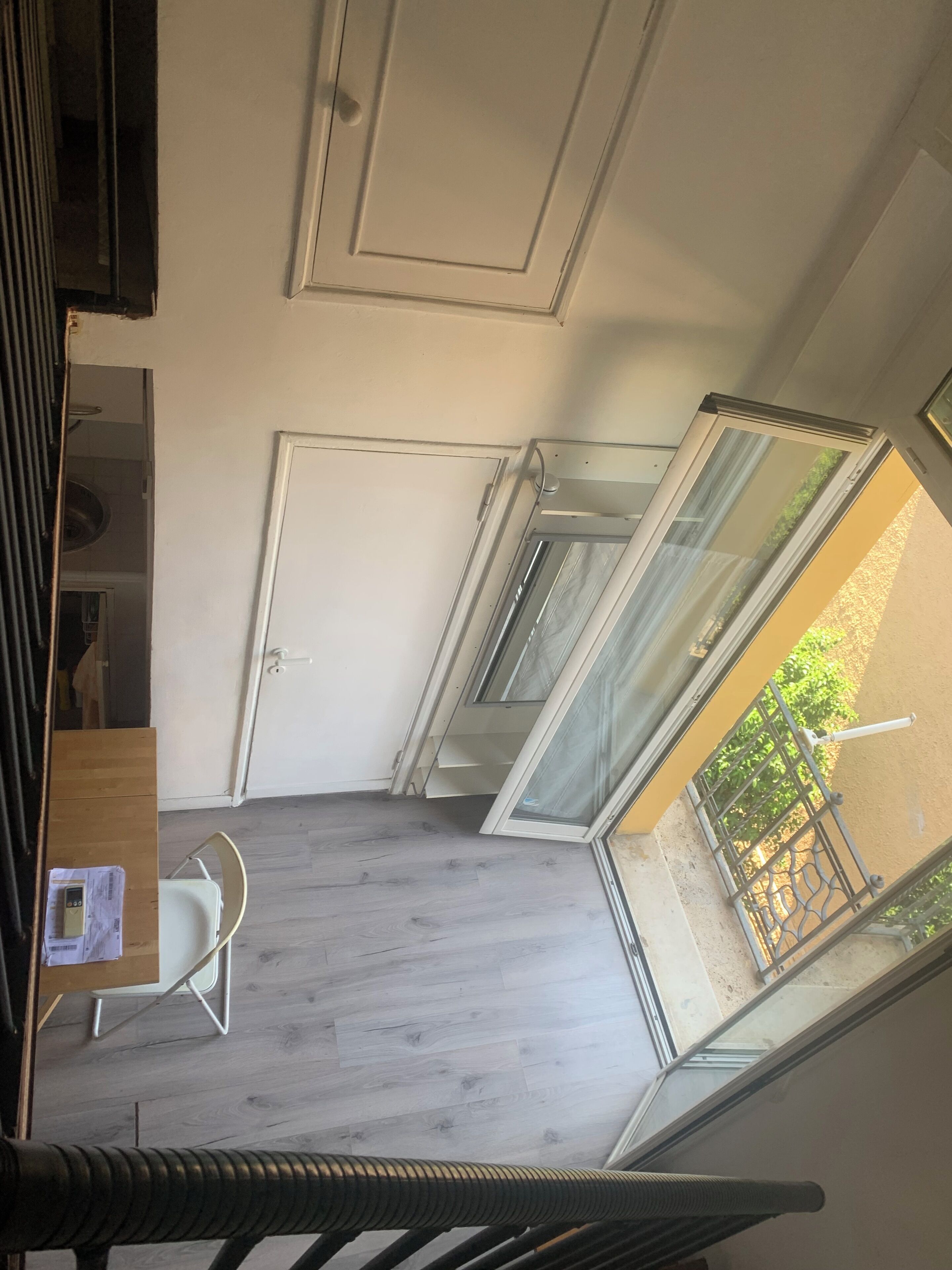 Ein Zimmer mit einer Schiebetür zum Balkon, einer weißen Tür und einem kleinen Tisch mit einem Stuhl.