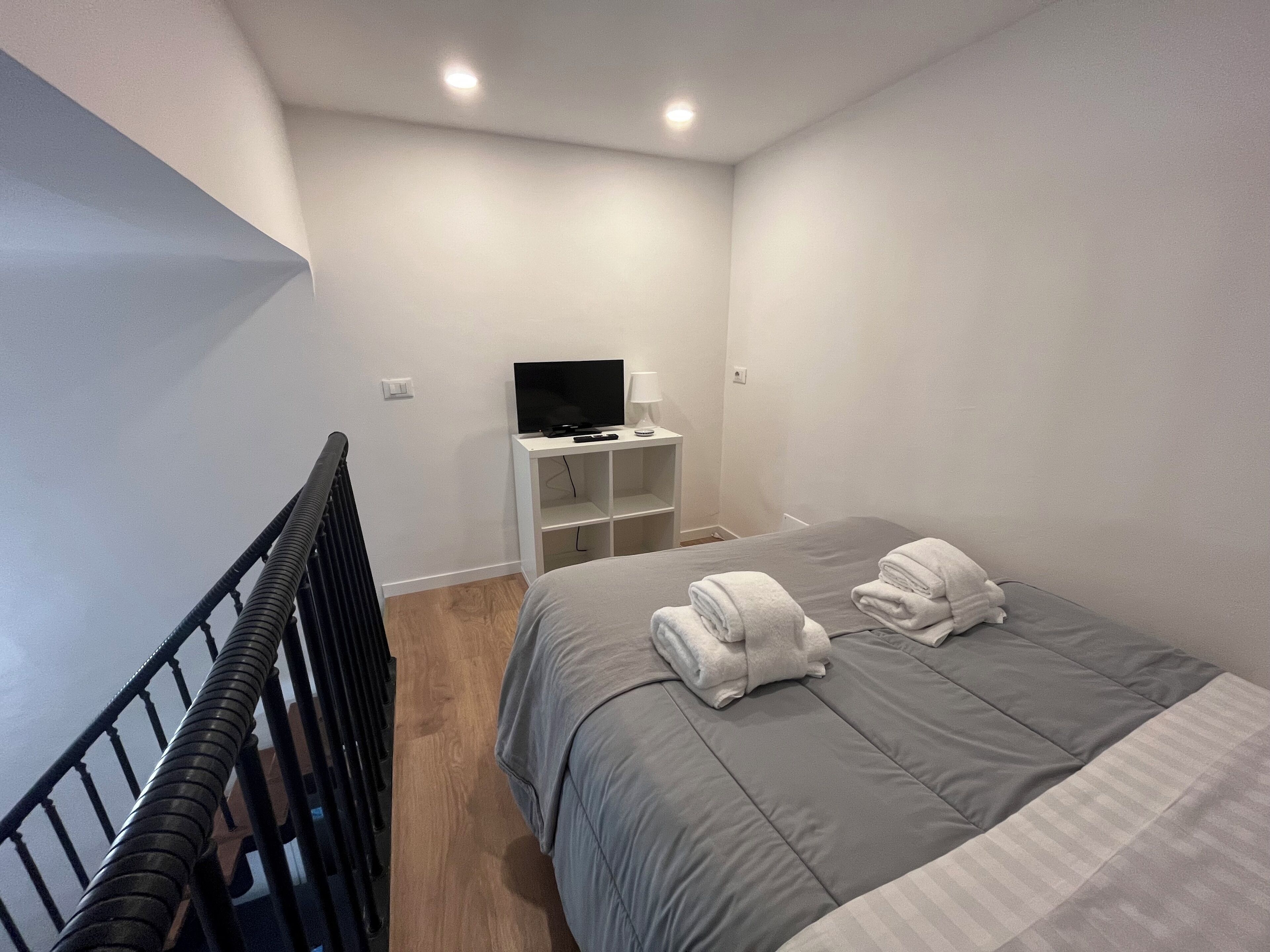 Una camera d'albergo moderna con un letto, una TV e una piccola scrivania.