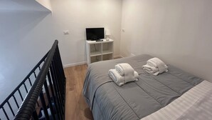 Una habitación de hotel moderna con una cama, un televisor y un escritorio pequeño.
