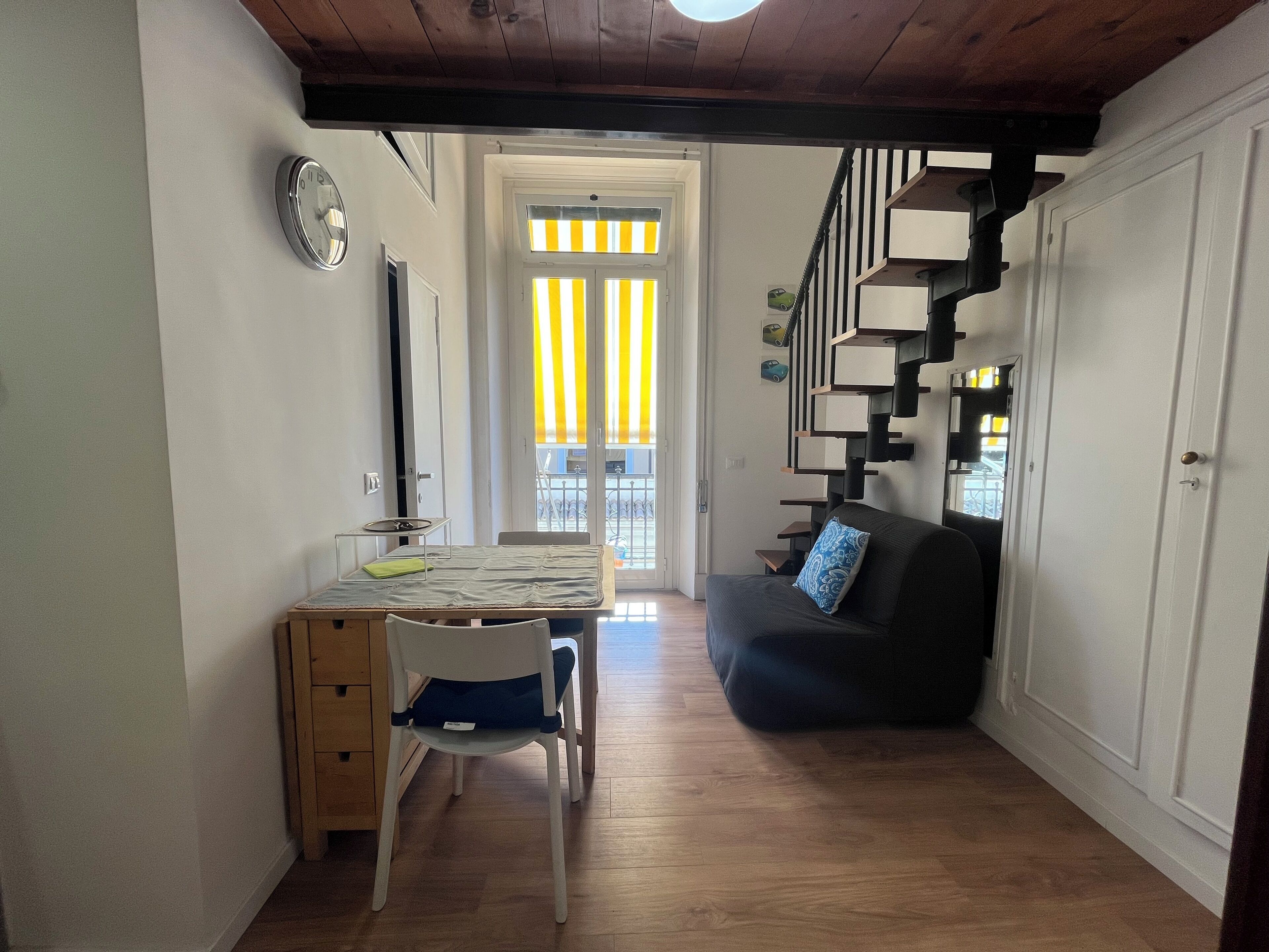 Ein kompakter Wohnbereich mit Essbereich, einer Couch und einer Treppe.