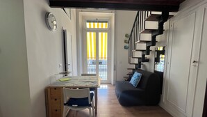 Un espacio habitable compacto con comedor, sofá y escalera.