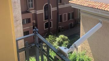 Vista da un balcone su un edificio con numerose finestre e un albero sullo sfondo.