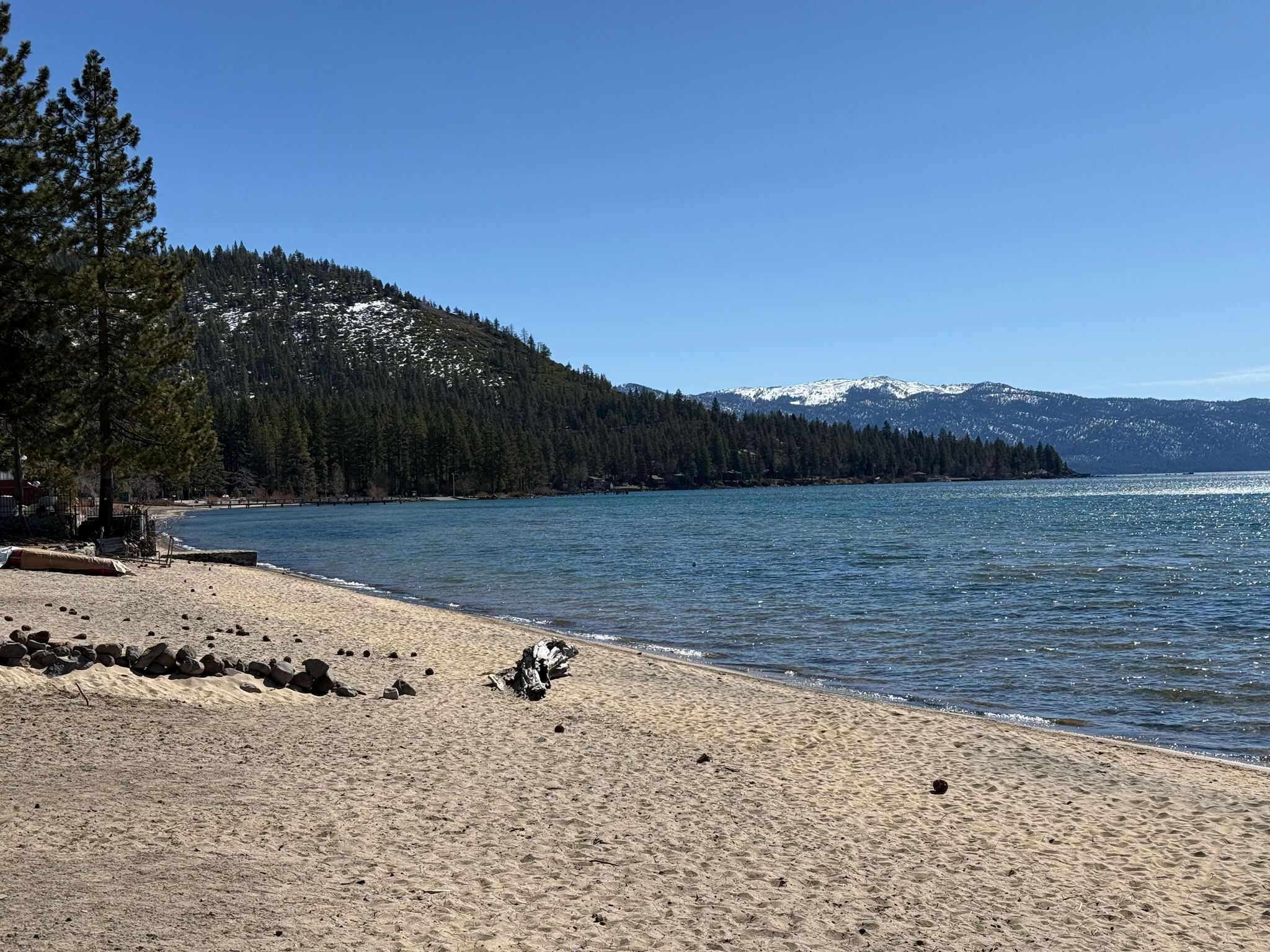 A beach with a clear view of a forested mountain range in the background.
