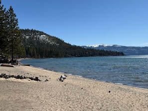 A beach with a clear view of a forested mountain range in the background.