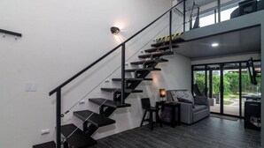 A modern interior with a staircase, a seating area, and a view of the outdoors.