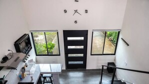 A modern kitchen with a black door, two windows, and a staircase.