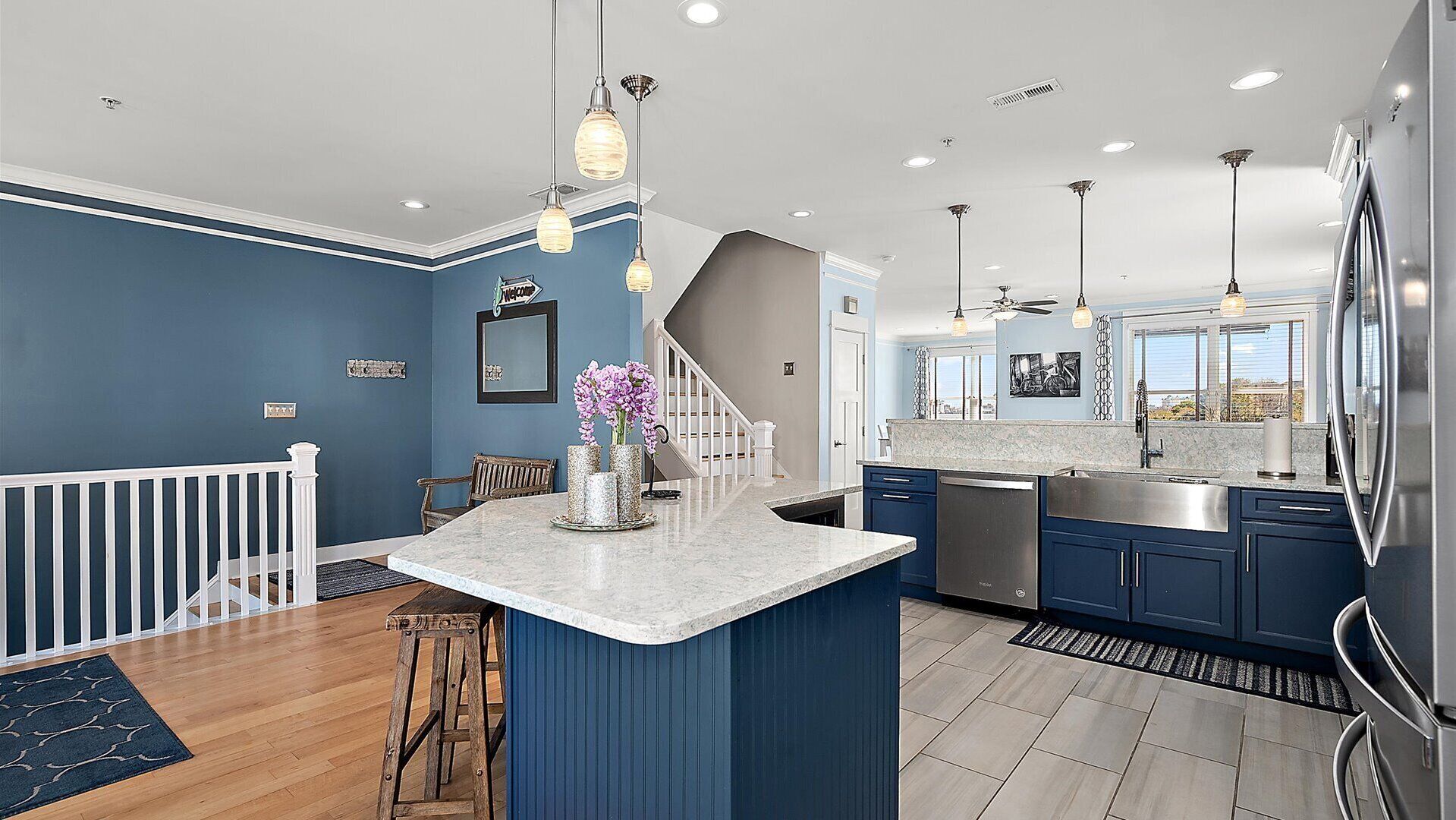 A modern kitchen with blue cabinetry, a central island, and pendant lighting.