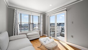 Una sala de estar moderna con un sofá, una mesita y vistas de la ciudad a través de grandes ventanales.