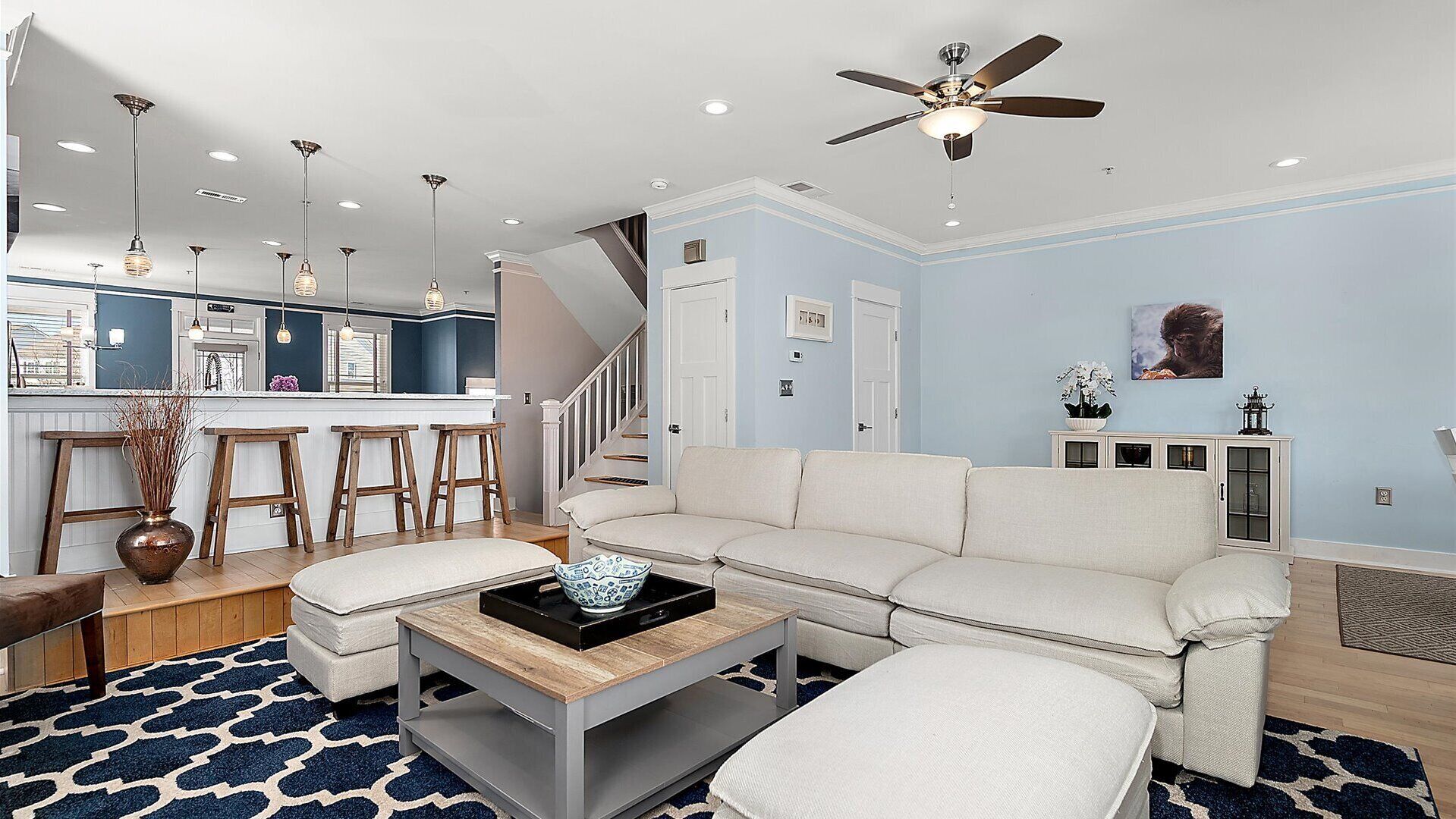 A modern living room with a white sofa, a coffee table, and a kitchen area with bar stools.