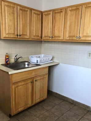 Cocina con armarios de madera, un lavabo y una encimera blanca.