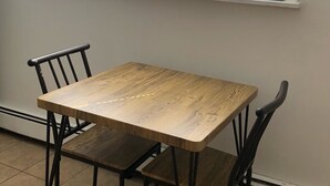 A dining table with four chairs, a window with blinds, and a tiled floor.