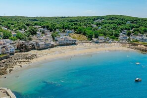 Une ville côtière dotée d’une plage de sable, d’eaux bleues et limpides, et de maisons qui bordent le rivage.