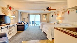 Une chambre d’hôtel avec un lit, un bureau, une chaise, une télévision et un balcon avec vue.