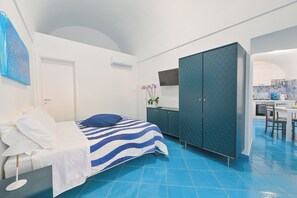 A bedroom with a bed, a wardrobe, a desk, and a small kitchen area. - Chiaia Di Rose Rooms & Apartment (Sant'Angelo)